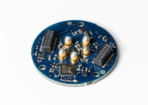 Circular blue sensor circuit board with connectors and five gold capacitors, mounted on a white background.