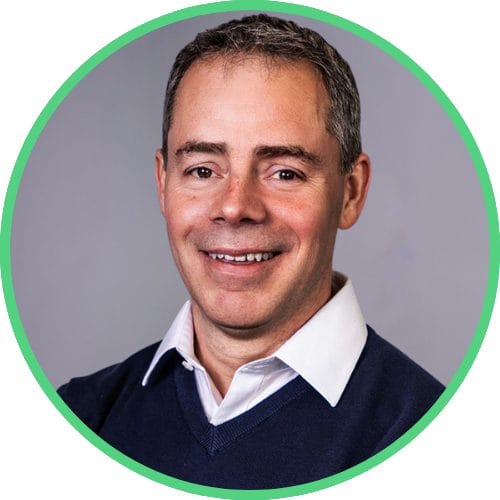 Emailer Profile Pics | ION SENSE Head-and-shoulders portrait of a smiling man in a white shirt and navy sweater, with a green circular border.